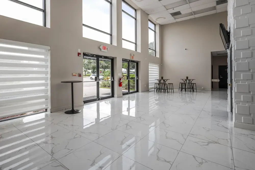 Modern, bright lobby with large windows, marble floors, and minimalist furniture, creating an open and inviting space.