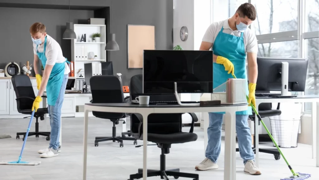 Male workers of cleaning service disinfecting in office